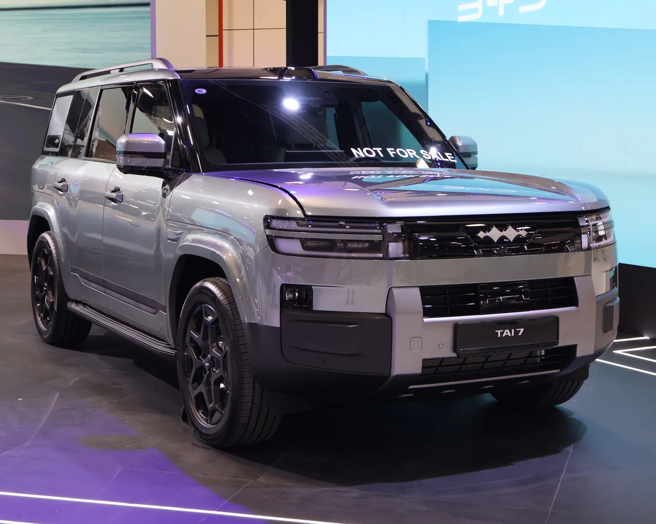 A silver Fangchengbao Ti7 show car at an indoor Singapore motor show. The windshield says “NOT FOR SALE” and the display plate says “TAI 7”.