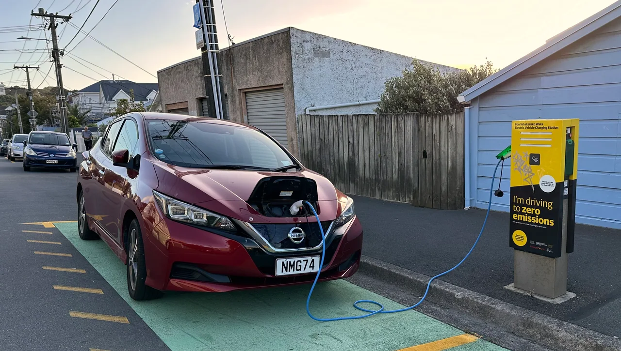 A red Nissan Leaf charging at a Wellington City Council station on Austin Street, Mount Victoria, photographed in February 2024.